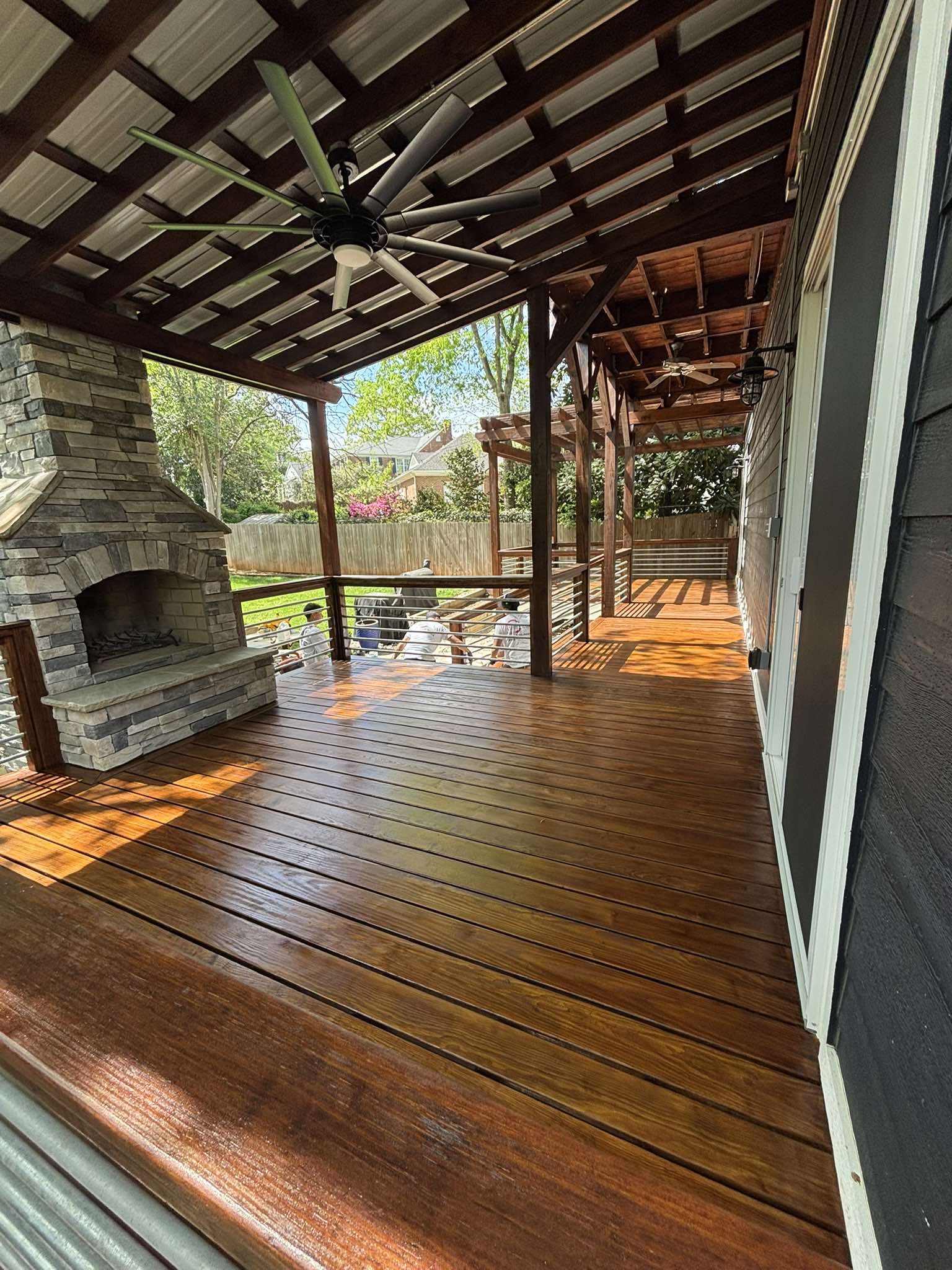Finished stained deck boards and covered overhead structure beside the outdoor stone fireplace